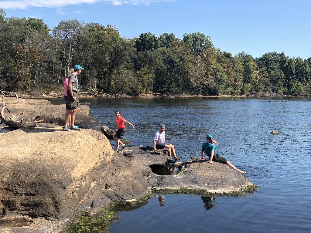 Scouts sitting on a rock in the middle of the Cape Fear river.